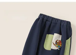 Detail of dark blue kids sports pants featuring a colorful embroidered pocket design