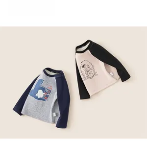 Dettaglio delle maglie in cotone con maniche raglan e stampe di pinguini e bambine