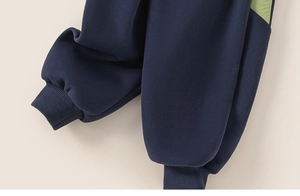 Detail of dark blue kids joggers with ribbed cuffs and green patchwork accents