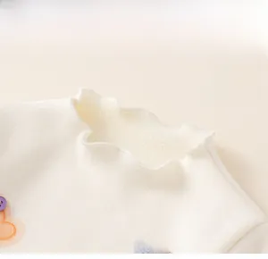 Close-up of white girls' sweatshirt featuring a lotus leaf collar and colorful buttons