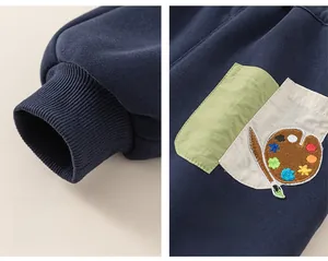 Detail of navy boy's sweatpants showing ribbed cuffs and colorful palette embroidery