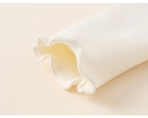 Detailed close-up of soft cotton knit sleeve with elegant ruffled lettuce edge cuff