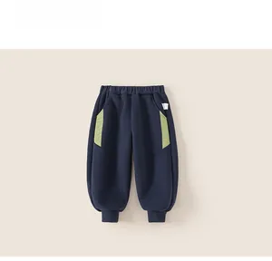 Detail of dark blue boy's joggers with elastic waist and green contrast pocket accents