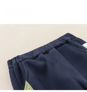 Detail shot of navy blue kids joggers featuring elastic waistband and green stitching