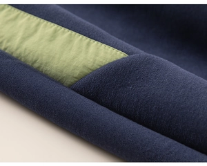 Detailed macro view of dark blue knit fabric with green woven stripe and precise stitching