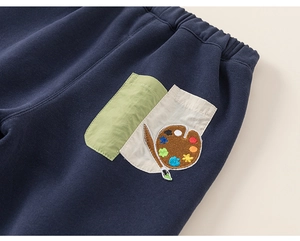 Detail of kids navy pants featuring a contrast pocket with embroidery and soft fabric texture