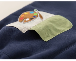 Detail of navy knit pants featuring a colorful palette embroidery and green cargo pocket