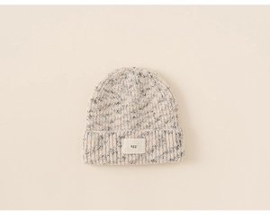 Detailed close-up of chunky knit mixed-color beanie with beige alphabet woven patch