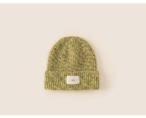Close-up of olive green cable knit beanie featuring a white woven letter label patch