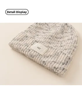 Detailed close-up of mixed yarn knit beanie with woven letter label and rolled cuff detail