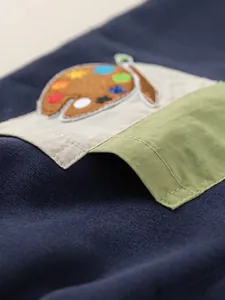 Navy blue knit boys pants featuring a contrasting avocado green pocket and art palette embroidery