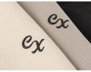 Détail du tissu en feutre beige et gris avec broderie cursive 'cx' noire précise