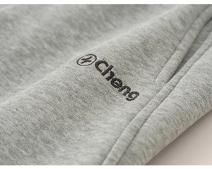 Vue macro du tissu en maille grise avec broderie du logo noir cheng sur un pantalon décontracté