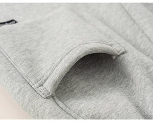 Détail des coutures renforcées de la poche kangourou et étiquette du pantalon de jogging