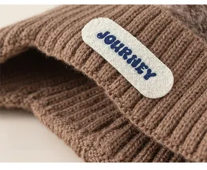 Close-up of deep brown chunky knit beanie with Journey patch and ribbed texture