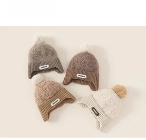 Detailed close-up of knit winter hats with ear flaps and fluffy pom-poms in earth tones