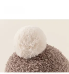 Detailed macro view of a soft plush pom-pom and brown textured knit on a winter hat