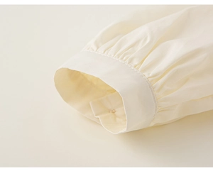 Primer plano de puños fruncidos con botones en una blusa de estilo académico para niña
