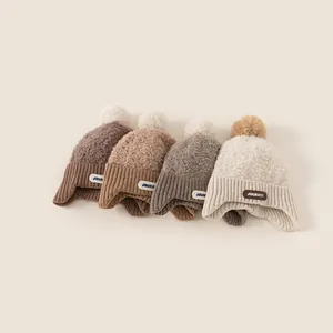 Winter knitted earflap hats for kids in earth tones with pompom and Journey leather label