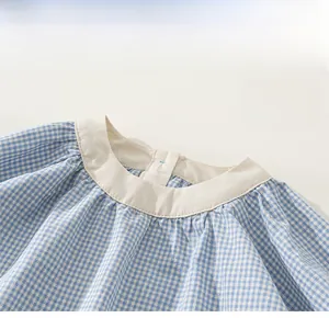 Dettaglio dell'abito vichy blu per bambina con scollo rotondo e rifiniture a pieghe