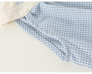 Close-up of blue gingham cotton fabric with fine stitching for toddler princess dress