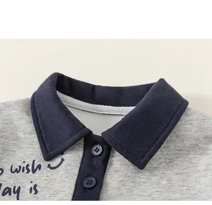 Detail of grey kid's polo shirt featuring navy contrast collar and button placket