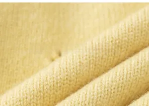 Close-up of pale yellow knit texture showing the delicate stitch pattern of the cardigan