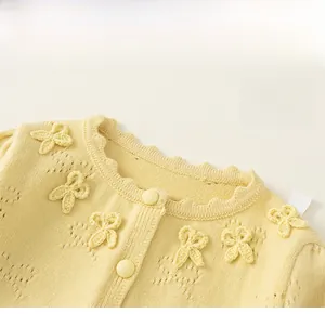 Close-up of baby girl yellow knit cardigan featuring scalloped collar and bow details