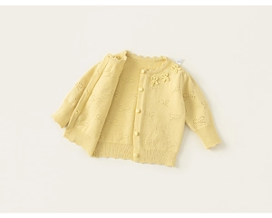 Detailed macro view of yellow knit cardigan featuring hollow bow patterns and lace edges