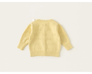Detail of light yellow knit cardigan with delicate bow-shaped hollow patterns and ruffled collar