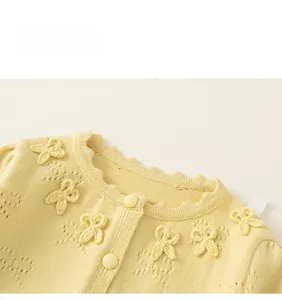 Detail of yellow knit cardigan with cutout texture and handmade bow accents