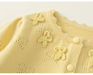 Detail of light yellow knit cardigan featuring hollow heart patterns and 3D bow accents