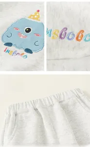 Detail of baby grey joggers showing cartoon monster embroidery and elastic waistband