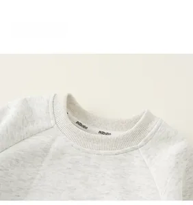 Detail of grey crewneck sweatshirt featuring raglan sleeves and ribbed neckband