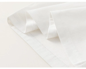 Macro shot of white knit cotton fabric showing premium double-needle stitching on hemline