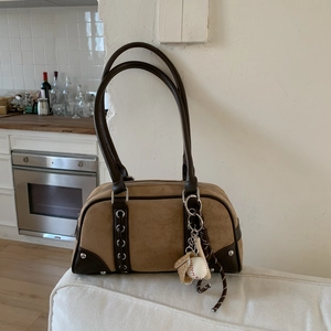 Detailed view of brown suede handbag with leather trim and baseball theme charm decoration