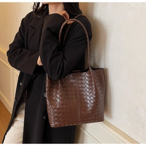 Detail view of dark brown woven leather tote bag with thick interlaced grid pattern