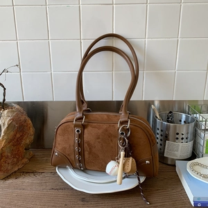 Detail of dark brown suede boston bag with leather panels and baseball charm set