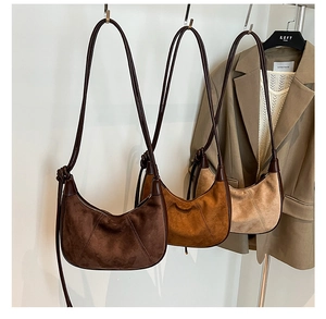 Detail view of suede hobo bags in brown and caramel tones hanging on a display