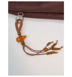 Dettaglio di ciondolo in legno e corda intrecciata su una borsa tote in pelle scamosciata