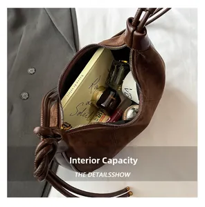 Top view of spacious interior of brown suede hobo bag with daily essentials inside