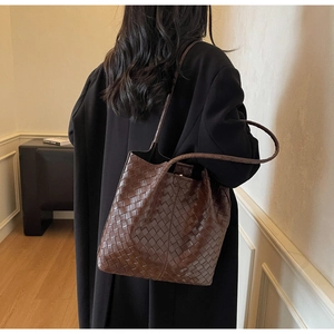 Detailed view of dark brown woven tote bag featuring classic intricate intrecciato texture