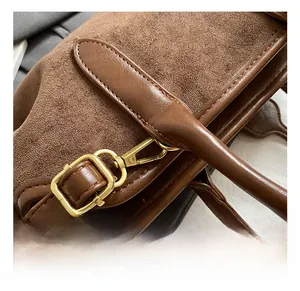 Détail des crochets en métal doré et des coutures sur le sac en daim marron mat rétro