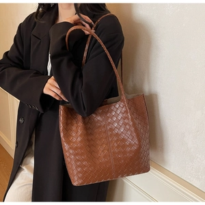 Detailed close-up of brown woven leather tote bag texture and fine cross-stitch craftsmanship