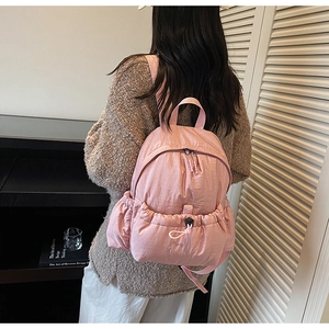 Detailed view of pink nylon backpack with drawstring pocket and side elastic pockets