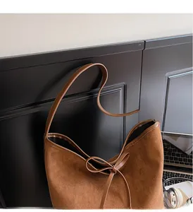 Détail d'un sac cabas marron mat en similicuir avec nœud décoratif et fines bandoulières