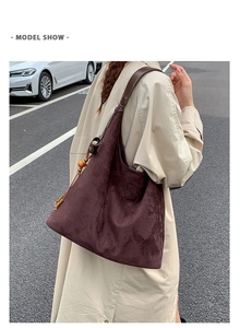 Dettaglio della borsa tote in pelle scamosciata marrone scuro con nappa in legno retrò