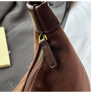 Detail of premium brown suede bag showing golden zipper and leather strap attachment