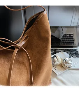 Détail du sac cabas en daim marron avec cordon en cuir et accessoires d'ordinateur