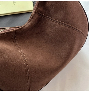 Detailed macro view of the brown suede handbag featuring precise double-stitch sewing lines
